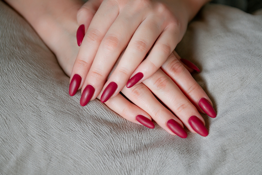 Model woman showing red shellac manicure on the long nails